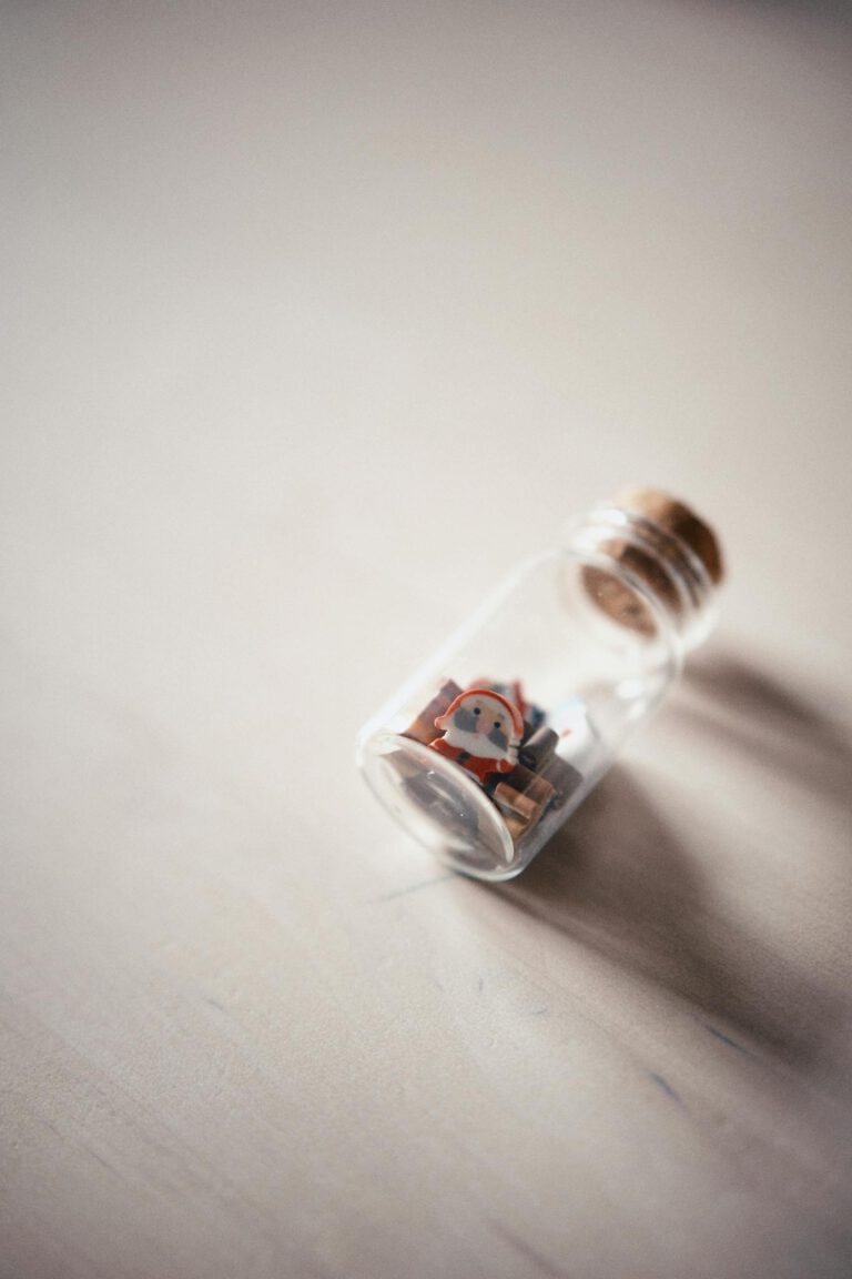 A whimsical miniature house sealed inside a glass bottle on a light surface, creatively photographed.