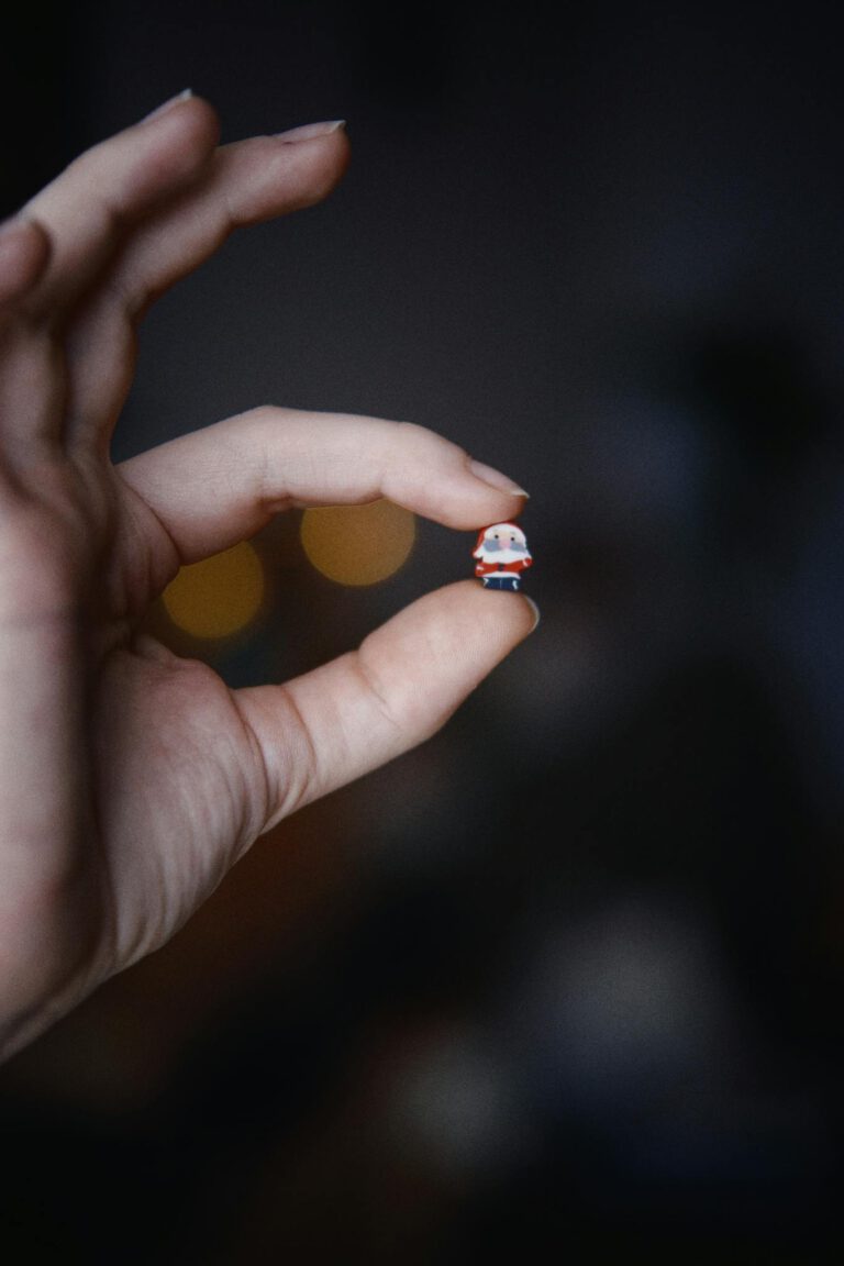 Close-up of a hand holding a tiny figurine against a blurred background.