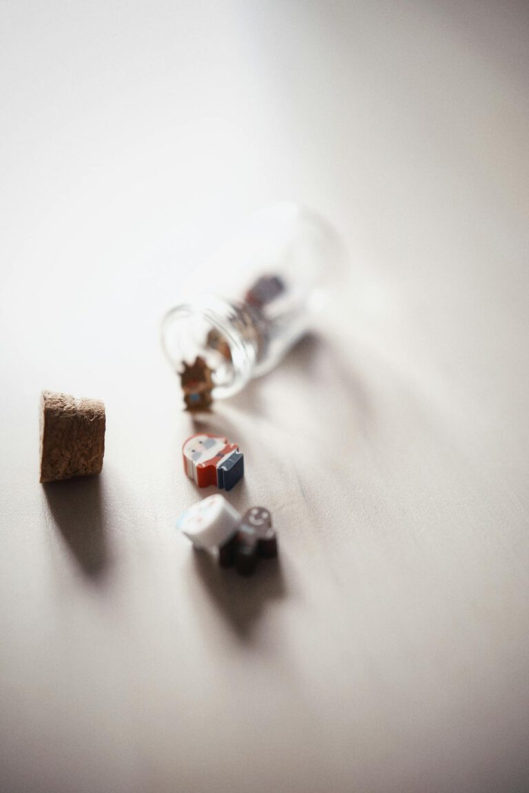 Close-up view of colorful miniature blocks spilling from an open glass bottle on a smooth surface.